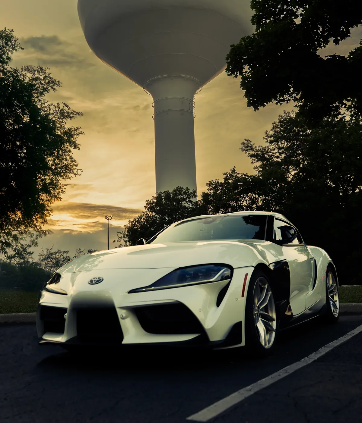 White Toyota Supra at sunset beneath a water tower